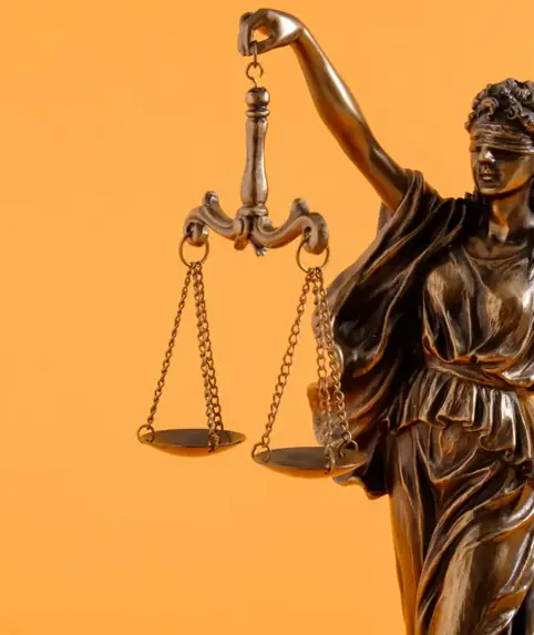 Bronze statuette of Lady Justice holding scales against an orange backdrop