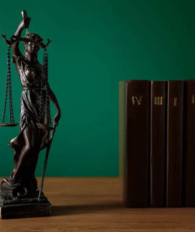 Bronze statuette of Lady Justice standing beside a row of leather law books